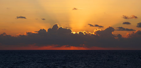orange rays of the setting sun over the sea horizon.
