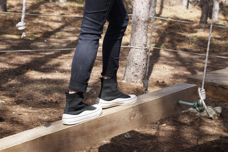 girl balancing on wooden beam in obstacle course outdoors.