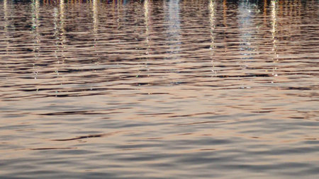 Coastal evening lights reflecting in sea water, blurred water background.の写真素材