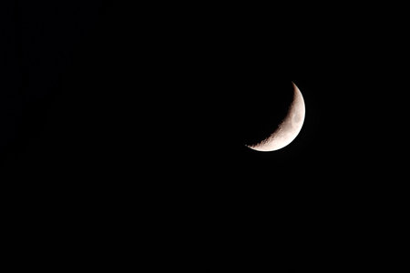 A telescope photo of the waxing moon in a black sky, copy space.