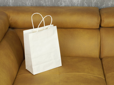 Close-up of a white paper bag on a yellow sofa.の写真素材