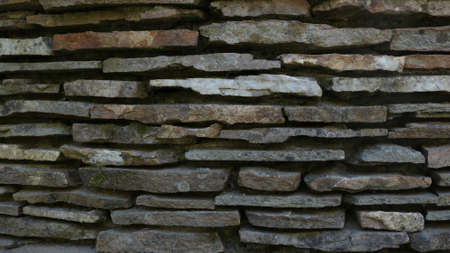 decorative wall of gray narrow flat rough stones making up natural textured embossed backgroundの写真素材