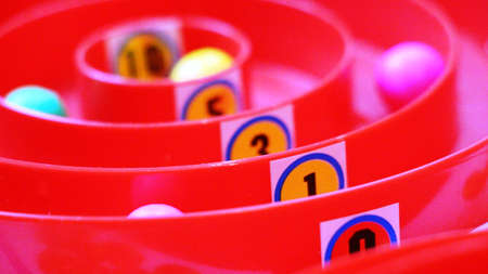 red plastic board game with number markings of points on circular paths along which colorful balls roll chips for family fun, illustration of the distribution of seats with emphasis on the number oneの写真素材