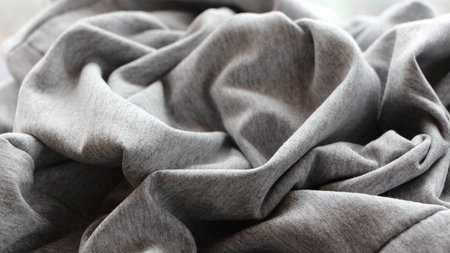 gray knit fabric crumpled with casual folds forms a textured solid background, soft cotton fabric...