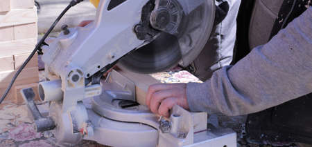 sawing off wooden blocks on a woodworking end machine, a carpenter at work at a bevelling machine, a...