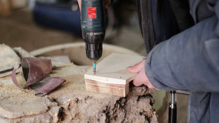 fixing a screw with an electric screwdriver in a wooden part close-up, fastening wooden fragments...
