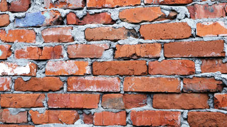 fragment of an old destroyed wall made of orange chipped bricks and abundant dried mortar, antique...