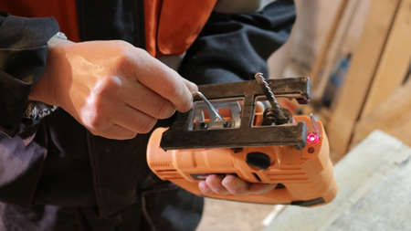 close-up electric jigsaw tilt adjustment, jigsaw tilt adjustment by carpenter's hands, hand...