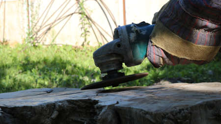 side view of a machine for grinding surfaces in the hands in fabric gloves working on a part of a...