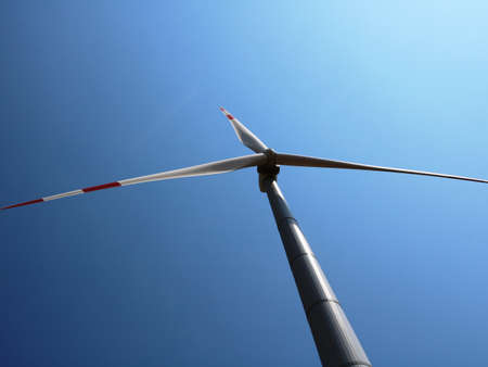 a propeller of a wind turbine with three blades against a blue sunny sky, the use of energy...