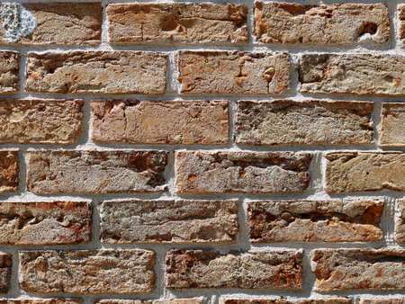 orange and beige brick wall in sunlight close-up fragment, part of old brickwork from sand-colored...