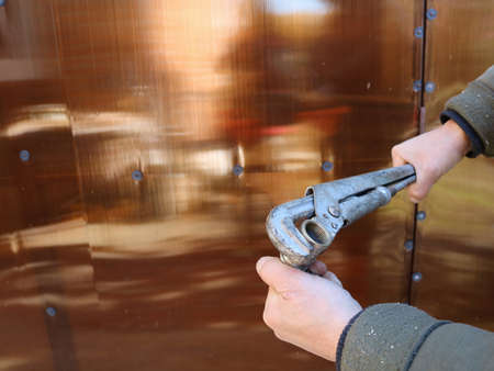 a gas wrench and a detail of fittings in the hands of a man making an effort against the background...