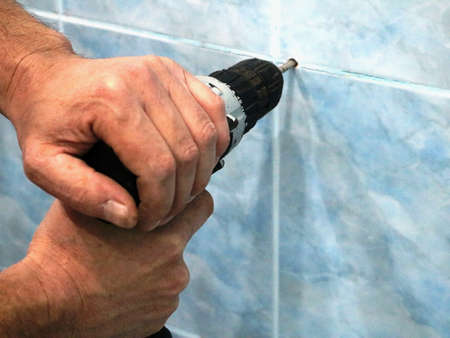 making a hole in a tiled wall with force using a puncher, drilling a wall in a bathroom in a seam...
