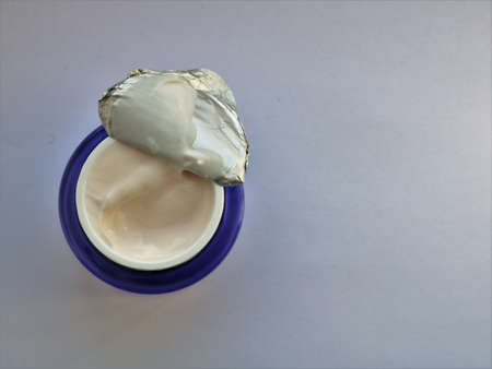 moisturizing cream jar with a slightly opened foil package top view on light background, isolated new object of care cosmetics top view, face skin care productの写真素材