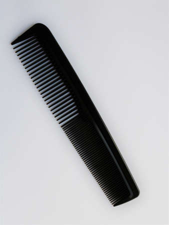 black plastic comb with frequent and sparse teeth, barber tool isolate on white background, dark household personal hygiene object on light surfaceの写真素材