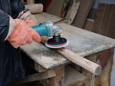 movement of an emery disc on a grinder in the hands of a carpenter polishing a long wooden stick on...