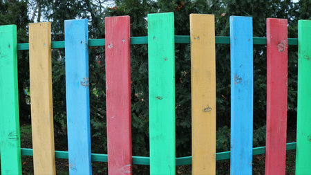 colorful painted wooden texture plank fence in a park or garden, multicolored wooden plank barrier...