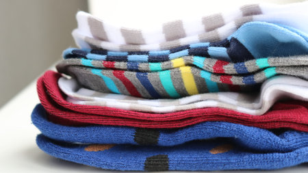 a stack of striped multi-colored children's socks lying on a light table close-up, home clothes in...