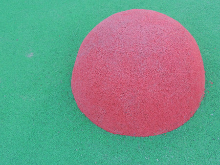 Textured two-tone elements in the structure of a sports abstraction, a convex half of a pink ball on a green background in pastel shades, a fragment of a children's outdoor floorの写真素材