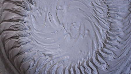 Gray thick viscous mortar with a circular ribbed pattern on a soft surface as an abstract textured...