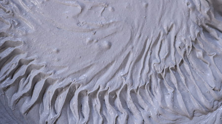 A thick gray mortar with a circular ribbed pattern on a soft surface, creating an abstract textured...