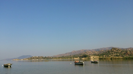 Three boats in the calm sea with mountains の素材