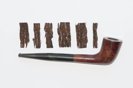 old wooden smoking pipe and pieces of pressed tobacco close-up on white