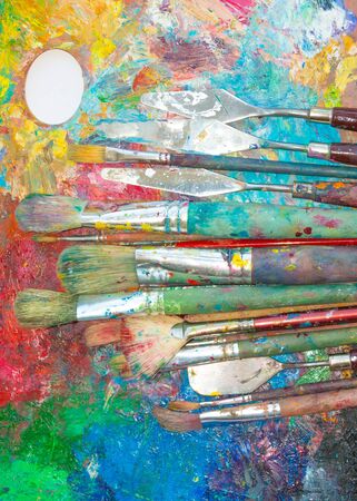 Palette with oil paints and many big and small brushes and palette knife on it close-upの写真素材