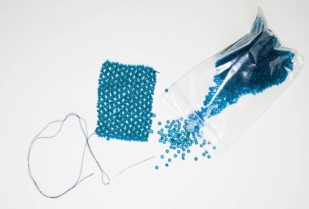 blue beads, woven beaded mesh, needle and beads in package on white background
