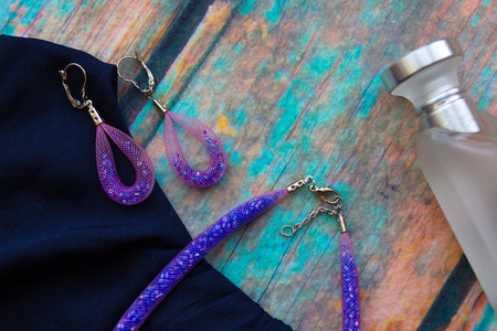 Necklace and earrings of the pink-blue harness, made of beads and jewelry grid lies on a blue satin...