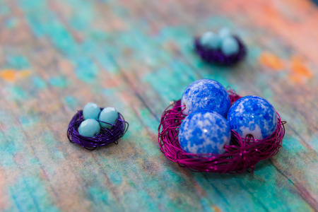 Decorative nest made from colorful beads and wire on the backdrop of blue old wooden surfaceの写真素材