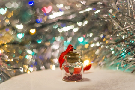 decorative bottle with red beads inside close-up with tinsel and bokeh on the backgroundの写真素材