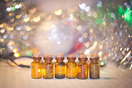 decorative bottle with dry flowers  beads and sparkles inside with tinsel and bokeh on the background shallow depth of fieldの写真素材