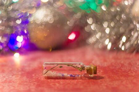 decorative bottle with dry flower and beads inside with tinsel and bokeh on the background shallow depth of fieldの写真素材