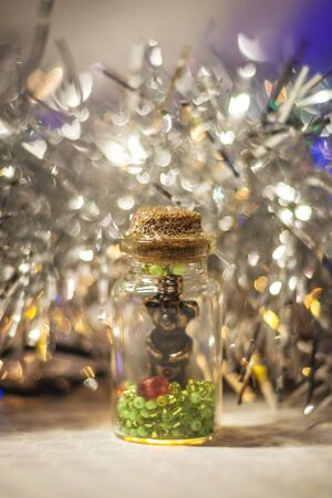 decorative bottle with beads and sparkles inside with tinsel and bokeh on the background shallow depth of fieldの写真素材