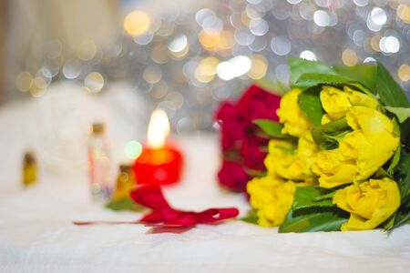 red and yellow small roses with red bow, heart shaped candles, small decorative bottles and bokeh on the background shallow depth of fieldの写真素材