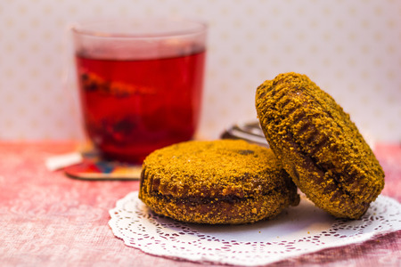 Fruit red tea tea bag pyramid in transparent glass of water and cakes on dotted background shallow depth of fieldの写真素材
