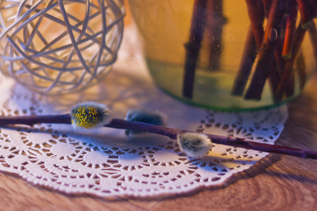 Willow branch lying near with a glass vase and ball of twigs close-up with bokeh on the background shallow depth of field toned pictureの写真素材