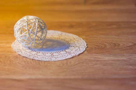 White ball of twigs decoration on a round napkin on background with wooden surface imitation shallow depth of field toned pictureの写真素材