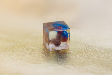 Flower inside of crystal made of epoxy resin close-up with bokeh on toned background shallow depth of fieldの写真素材