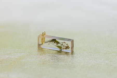 Flower inside of crystal made of epoxy resin close-up with bokeh on toned background shallow depth...