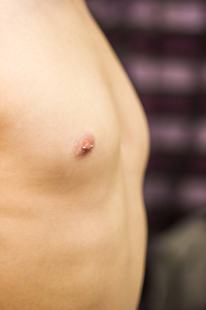 Pierced male nipple with steel straight barbell close-up shallow depth of fieldの写真素材