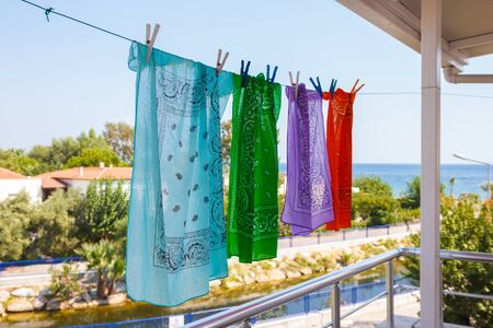 Four colored bandanas hang on a rope in the street overlooking the sea