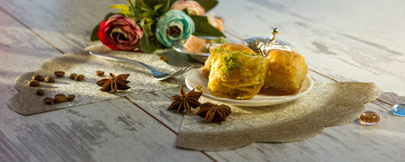 plate with baklava and lukum in lukumluk decorative flowers and badyan on sunny day on wooden table toned picture close-up shallow depth of fieldの写真素材