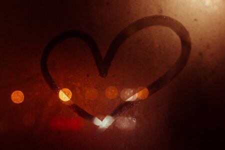 drawing of heart symbol on misted window with bokehの写真素材