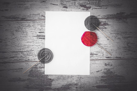 Flat lay with white sheet and three lollypops one of them is red on wooden background top view monochrome toned pictureの写真素材