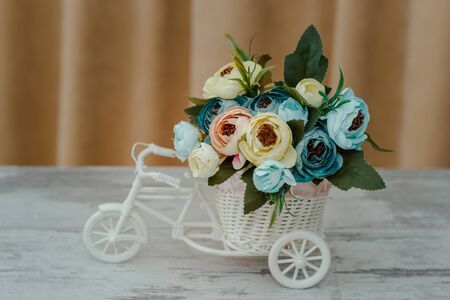 artificial flowers in decorative pot in the form of a bicycle. Close-up, shallow depth of fieldの写真素材