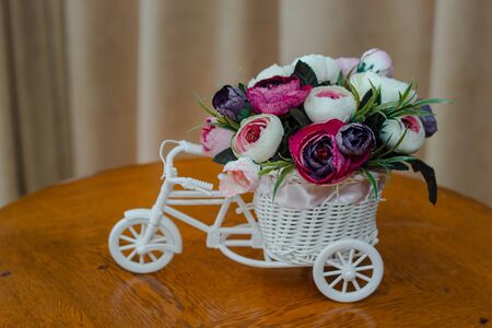 artificial flowers in decorative pot in the form of a bicycle. Close-up, shallow depth of fieldの写真素材