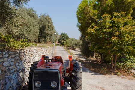 Red tractor stands on the road to a house. Shoot at sunny dayの写真素材