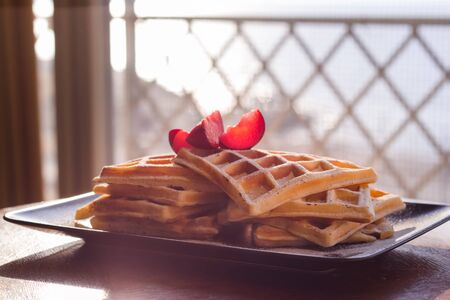Viennese waffles with icing sugar. Slices of plums. Close-up, shallow depth of field.
